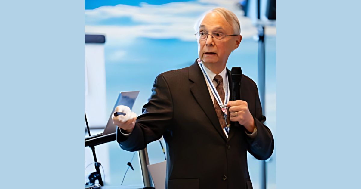 A well-dressed man in a suit and tie speaks confidently at a podium during a formal event.